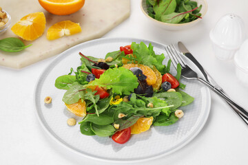 Delicious salad with tomatoes and orange slices served on white table