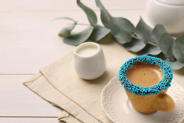 Delicious edible biscuit cup of espresso decorated with sprinkles on white wooden table, space for text