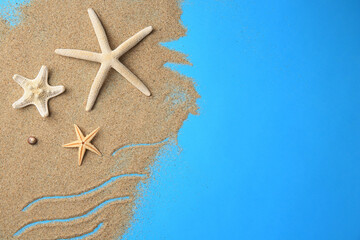 Fototapeta na wymiar Beautiful starfishes and sand on blue background, flat lay. Space for text