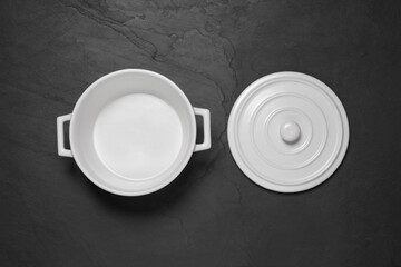 Empty white pot and lid on black table, flat lay