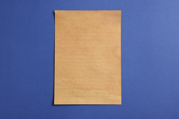 Sheet of old parchment paper on blue background, top view