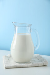 One jug of fresh milk on white table against light blue background
