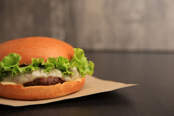 One tasty cheeseburger on wooden table, closeup. Space for text