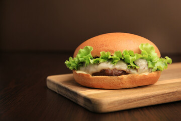 One tasty cheeseburger on wooden table. Space for text