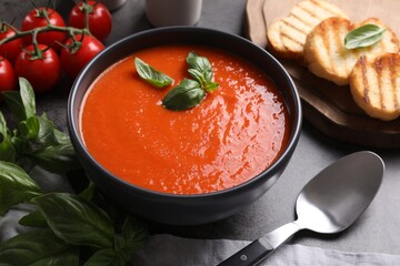 Delicious tomato cream soup in bowl served on grey table
