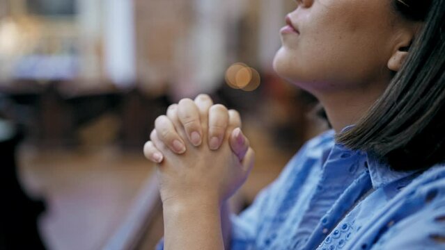 Young beautiful hispanic woman praying on a church bench at St. Karl Borrom&auml;us church