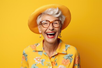portrait of a cheerful smiling elderly grandmother in glasses on a yellow background