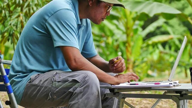 A gardener is checking information on the yield of his organic vegetables using a computer database. Modern farming concept without chemical fertilizers