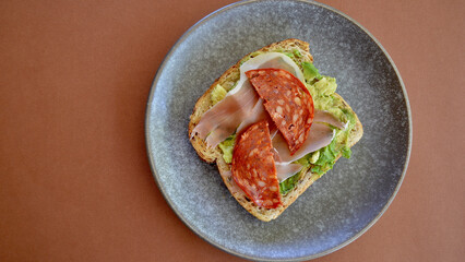 Toasted multi grain bread with smashed avocado and hot Italian salami