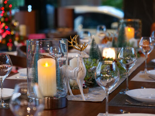 close up dining table setting for Christmas eve family party with deer decoration and wine glassse