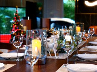 close up dining table setting for Christmas eve family party with deer decoration and wine glasses