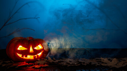 Naklejka premium Halloween pumpkin on a wooden background in a spooky atmosphere with candles and smoke
