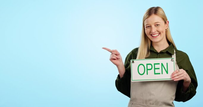 Happy woman, small business and pointing with open sign in advertising against a blue studio background. Portrait of female person or waitress showing billboard, poster or information on mockup space