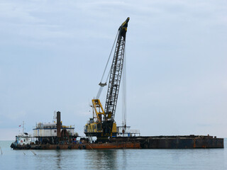 Fototapeta na wymiar a large floating dredging excavator on sea coast