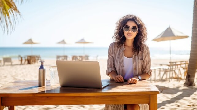 Young woman working on laptop from the beach