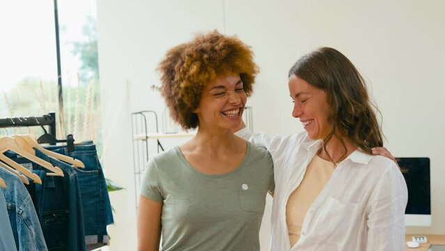 Portrait of two laughing women friends running online fashion business from home together - shot in real time