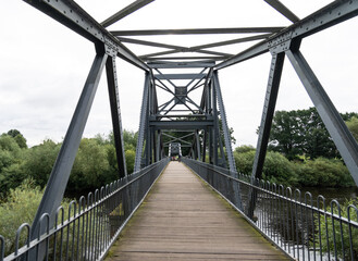 Fototapeta na wymiar walking across a steel foot bridge across the River Eden, near Carlisle, Cumbria