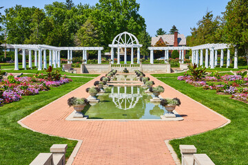 Brick pathway leading to pools of water and white pergola with trellises at Lakeside Park