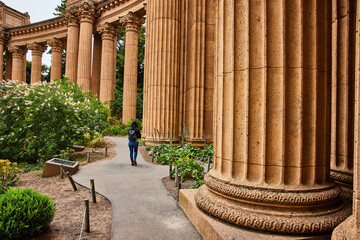 Person walking beside Ancient Roman colonnade architecture lookalike at Palace of Fine Arts
