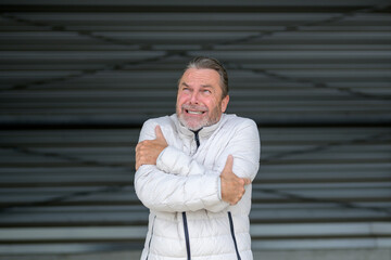 Fototapeta premium Man with a white winter jacket looking shivering at the sky