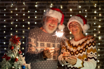 Happy senior family couple in Santa hat celebrate together with love Christmas and new year event night firing sparklers. Man and woman enjoy magic moment relationship at Christmas time