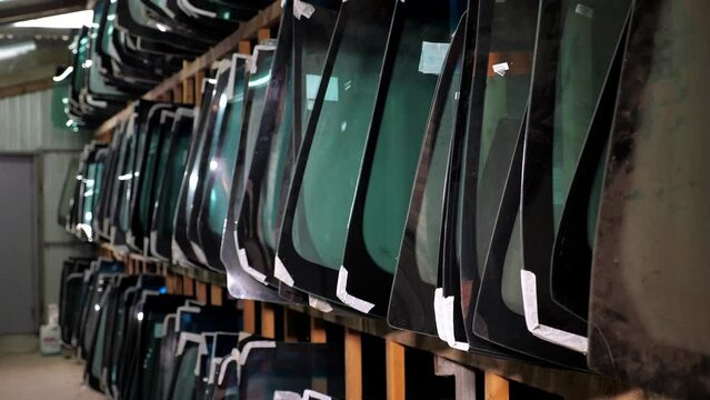 There are many different glasses for the car on the shelves of the car shop . New windshield and side windows on the shelves in the store. Salon for the replacement of car windows.