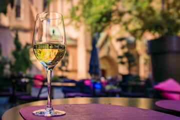 Glass of local Alsatian Gewurztraminer white wine at an outdoor table of a modern restaurant on Grande Ile, historic center of Strasbourg, Alsace, France