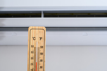 Klimatyzacja ścienna włączona i termometr wskazujący temperaturę w pomieszczeniu