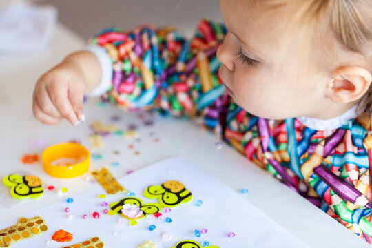 Toddler child in art smock gluing and sticking craft together