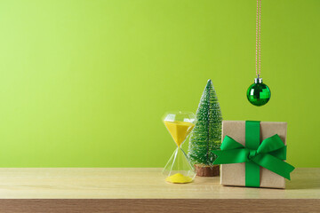 Christmas creative background  with gift box, pine trees and hourglass sand clock on wooden table