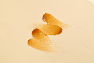 Isolated streaks of deep yellow cosmetics adorned on a beige background. Space available for brands...