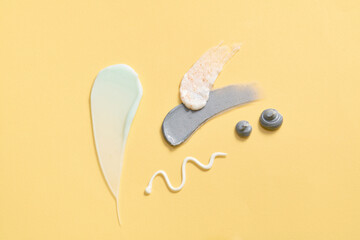 On a yellow background, streaks of dense-textured cosmetics are adorned. The scene is set for...