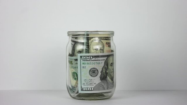 Person put many dollar money inside glass jar. Stop motion animation. A lot of usa green banknotes. Save up budget concept. Piggy bank. American bucks cash fund. Accumulate box. Us dolar sum. Pile usd