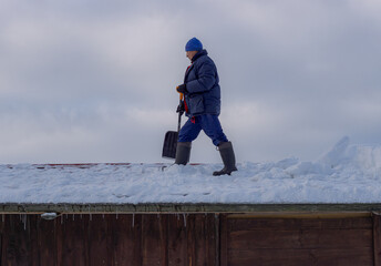 Man on the privat house roof top cleaning snow with shovel