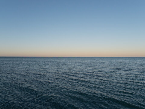 50:50 split calm blue sea and blue sky at dusk