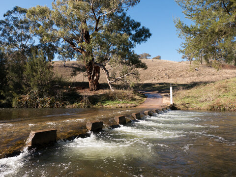 Gravel road with water running over concrete causeway