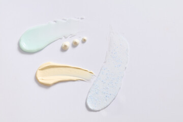 Different cosmetic textures of face cream, serum and exfoliating cream on white background. Cosmetics induce a smoother feel and appearance to the skin. Scene for advertising.