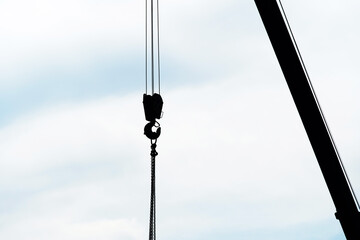Fototapeta premium A fragment of a crane hook and boom on a light sky background. Space. A shadow.