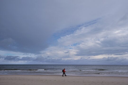 Silhouette of lonely person on beach in Hel Penisula in stormy autumn scenery. Pomerania, Poland