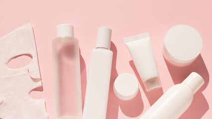 Set of cosmetic products for face care in white color on a pink background. Beauty. Self care. Moisturizing the skin of the face. Cream, face mask, serum, lip balm, toner, eye cream.