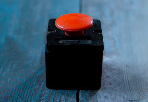 The concept of the threat of nuclear war. Red button on cold blue wooden background