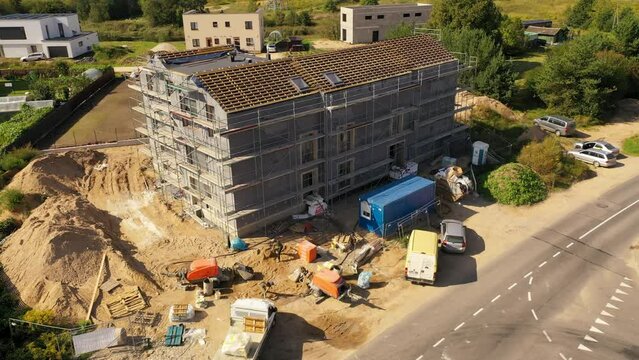 Drone footage of new residential house construction site, scaffolding and roofing