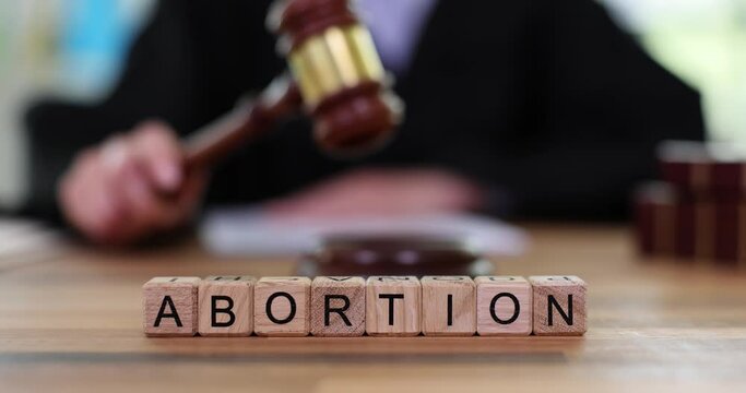 Word abortion and judge with gavel in courtroom. Ban on abortion and termination of pregnancy
