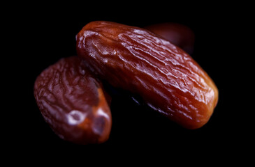 Several ripe dates on a black background. Delicious dates on black.