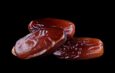 Several ripe dates on a black background. Delicious dates on black.