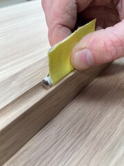 Closeup of hand sanding groove in wood