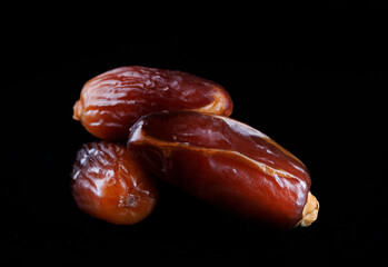 Several ripe dates on a black background. Delicious dates on black.