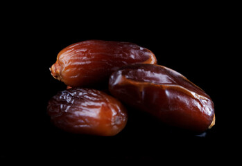 Several ripe dates on a black background. Delicious dates on black.