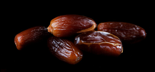 Several ripe dates on a black background. Delicious dates on black.