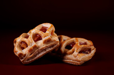 Puff pastry pastry with lingonberry jam on a dark red background. Cookies with lingonberry jam.